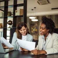 Two business women discussing paperwork.