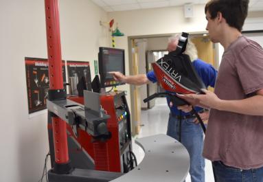 teacher showing student how to use welding simulator