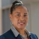 Woman wearing blue blazer and gray shirt smiling