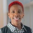 Woman with red hair wearing a black and white shirt smiling